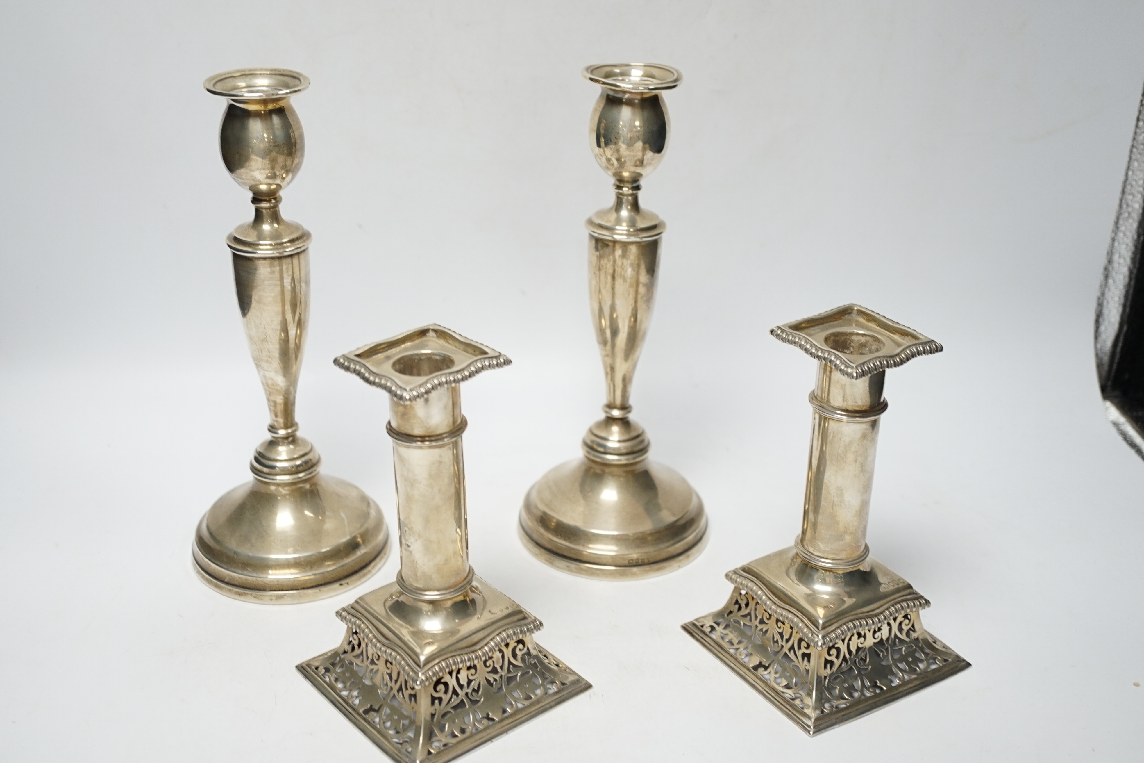 A pair of Victorian silver candlesticks, on pierced swept bases, William Leuchars, London, 1886, 15.2cm, weighted and a later taller pair of silver candlesticks.
